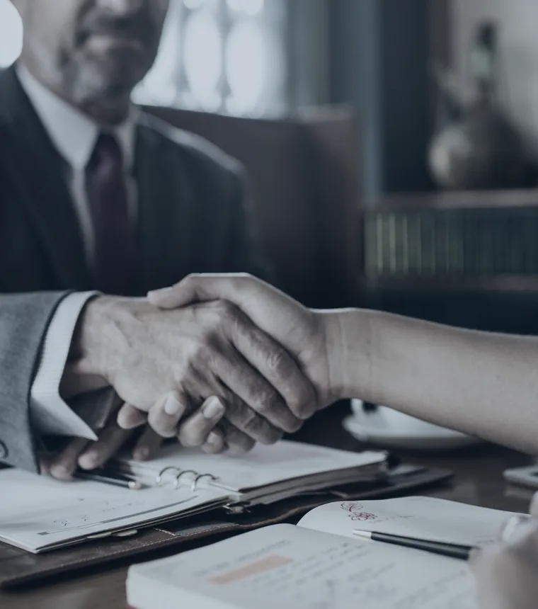 Attorney shaking hands with a client across a desk